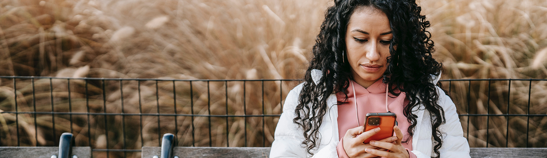 Photo of a young woman on a smartphone listening to music with earbuds